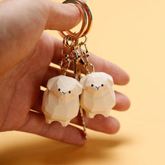 Close-up of a hand holding two wooden sheep keychains