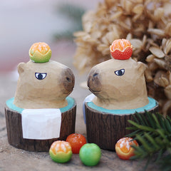 Two soaking bath shaped capybara sculptures, hand carved and painted from wood.