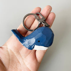 Close-up of the big head blue whale keychain held in a hand, showing its detailed design and color contrast.