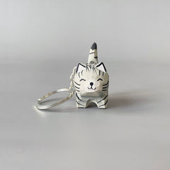 Front view of black stripe gray cat keychain with a smiling expression.