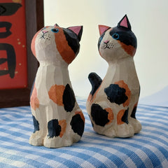Two hand-painted wooden calico cat figurines shown side by side