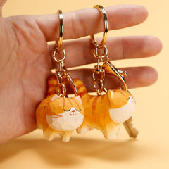 Two Chubby Orange Cat Keychains held in a hand, showcasing the keychains' details.