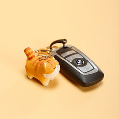 Close-up of chubby orange cat wooden keychain attached to car key