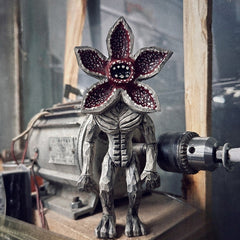 Demogorgon figure displayed in a workshop setting near a drill machine, emphasizing craftsmanship.