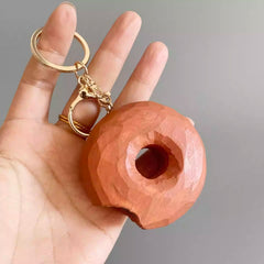 wooden donut keychain shown in hand for size reference