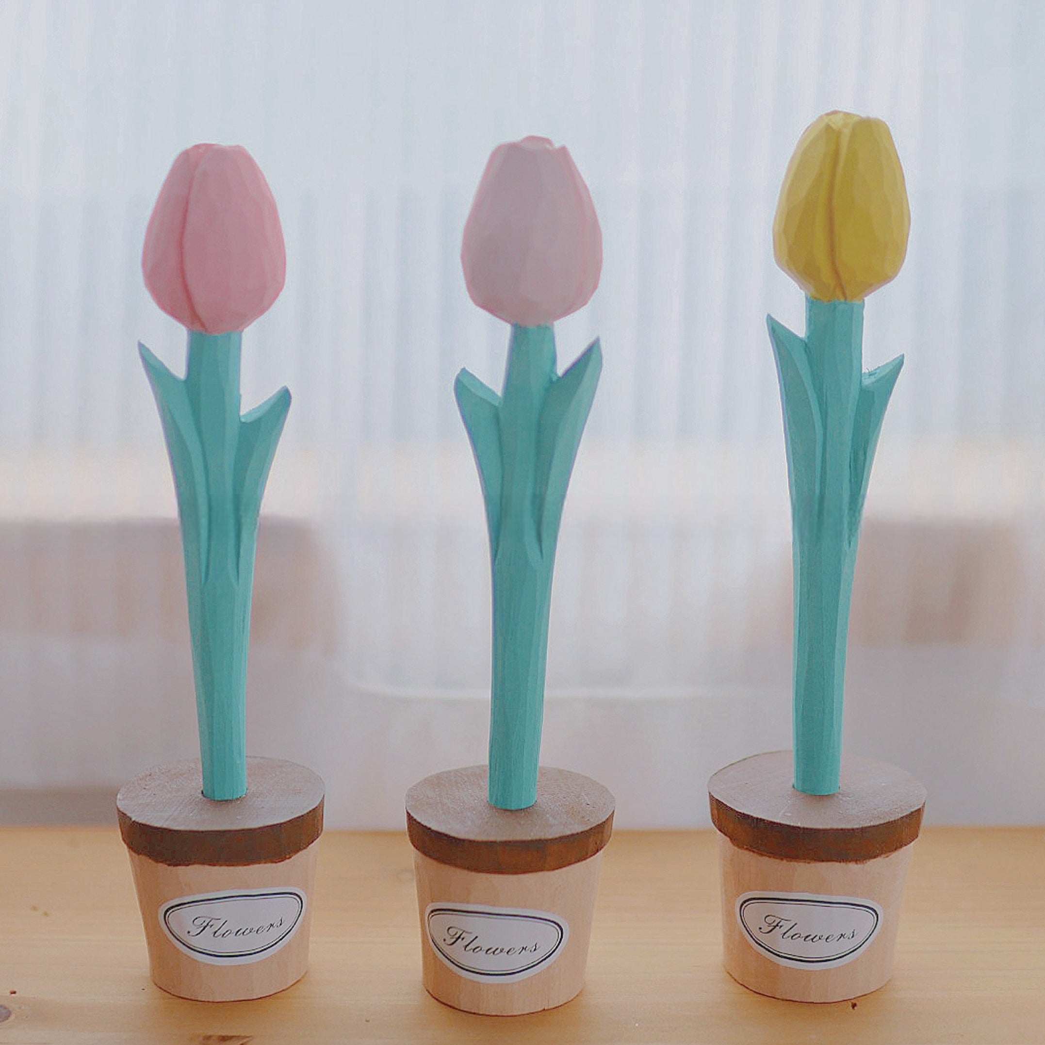 Three flower pens with pink, light pink, and yellow tulip shapes standing in small pots labeled "Flowers."