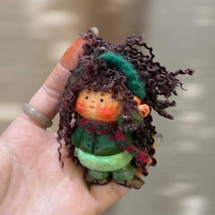 Side view of wooden doll keychain showing hand-carved wood body and cotton yarn curly hair