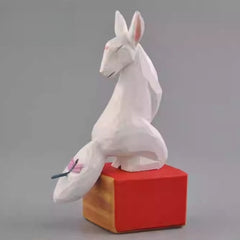 Hand-painted wooden kitsune figurine viewed from front angle
