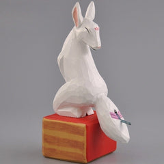 Hand-carved kitsune figurine in wood displayed on base