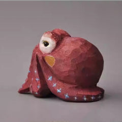 Side view of hand-carved red octopus figurine made from wood, featuring curled tentacles.