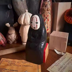 Hand-carved No Face Figure wooden sculpture displayed among other artisan figurines.