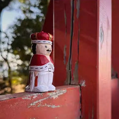 hand carved nutcracker figurine standing on wooden railing