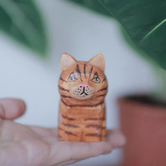 Orange cat wooden figurine in hand