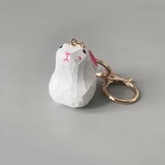 Close-up of a cute bunny keychain, featuring a white body and pink ears, attached to a golden keyring.