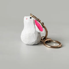 A handmade bunny keychain with a white body and bright pink ears, shown standing upright with a keyring attached.