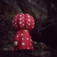 Red polka dot pumpkin head wooden figurine in forest setting