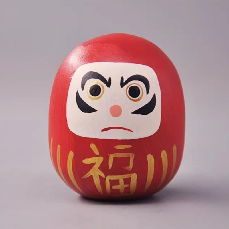 Red daruma doll with gold fortune character on front
