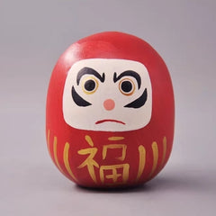 Red daruma doll with gold fortune character on front