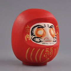 Side view of red wooden daruma doll