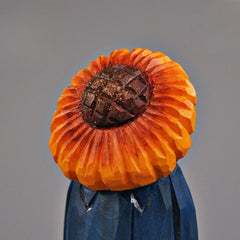 Close-up of the sunflower head on a hand-carved wooden figure, showing texture and detail.