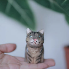 Tabby cat wooden figurine in hand