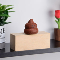 Artisanal toy poop with a friendly face, displayed among wood shavings.