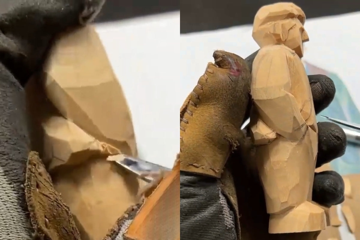 Refining wooden coat edges and carving raised folds with a knife to enhance depth on hand carved wood figurine.