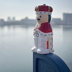 hand carved wooden nutcracker figurine displayed outdoors by water